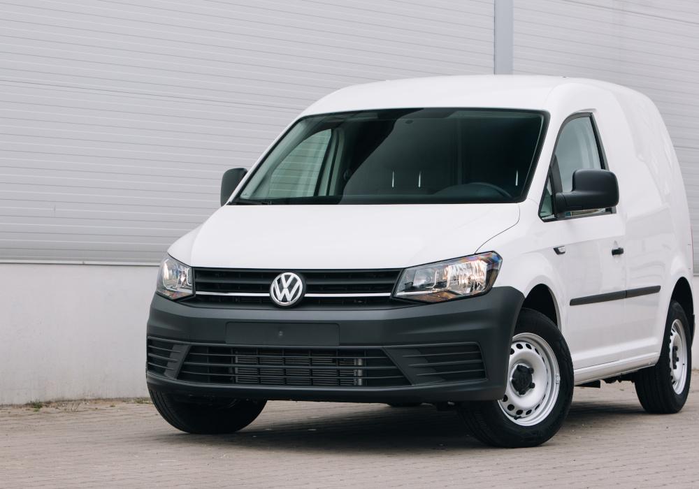 Exterior front shot of white Volkswagen Caddy infront of warehouse building