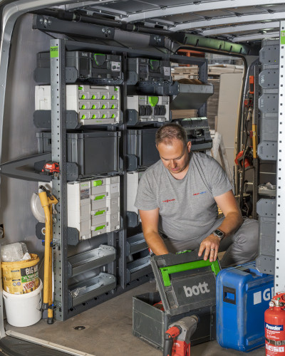 Man working in back of van - van racking with van storage boxes fitted behind him